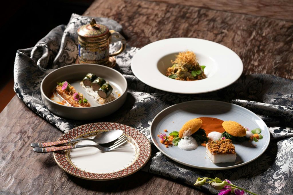 고급 요리, 화려한 찻주전자, 식기가 무늬 천에 놓인 우아한 테이블입니다.