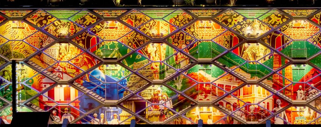 기하학적 격자 구조로 둘러싸인 문화적, 역사적 요소가 생생하게 묘사된 건물의 외관.