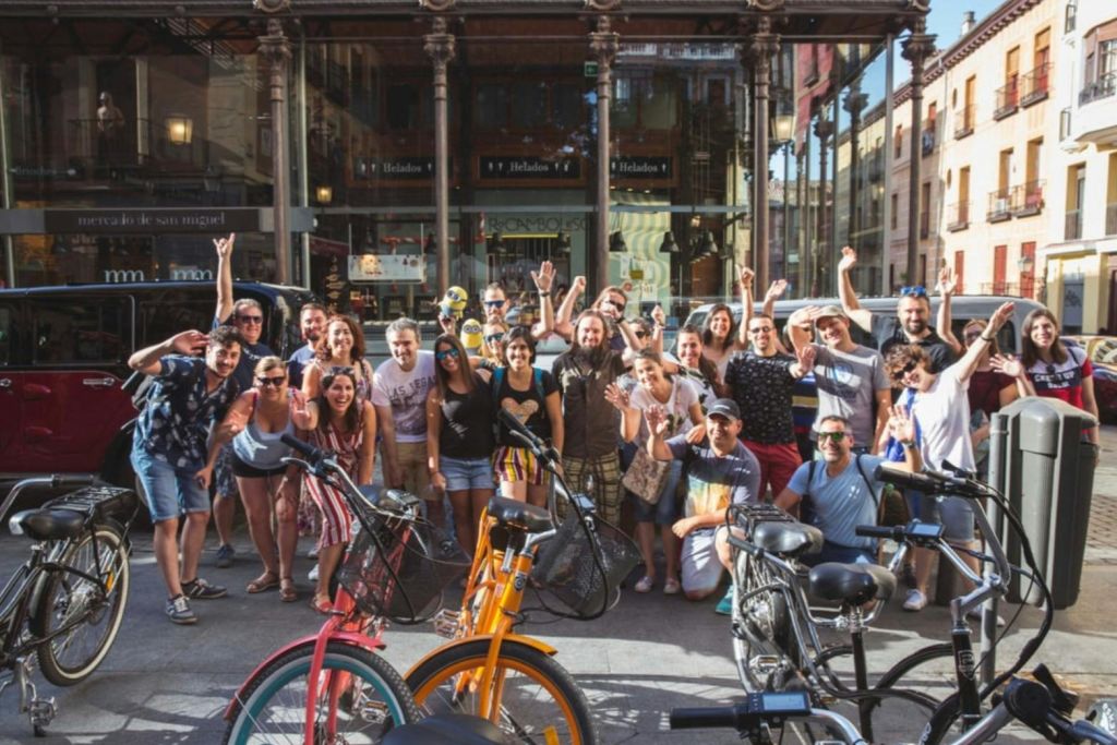 한 무리의 사람들이 상점 앞에서 자전거를 들고 미소를 지으며 사진 촬영을 위해 포즈를 취하고 있습니다.