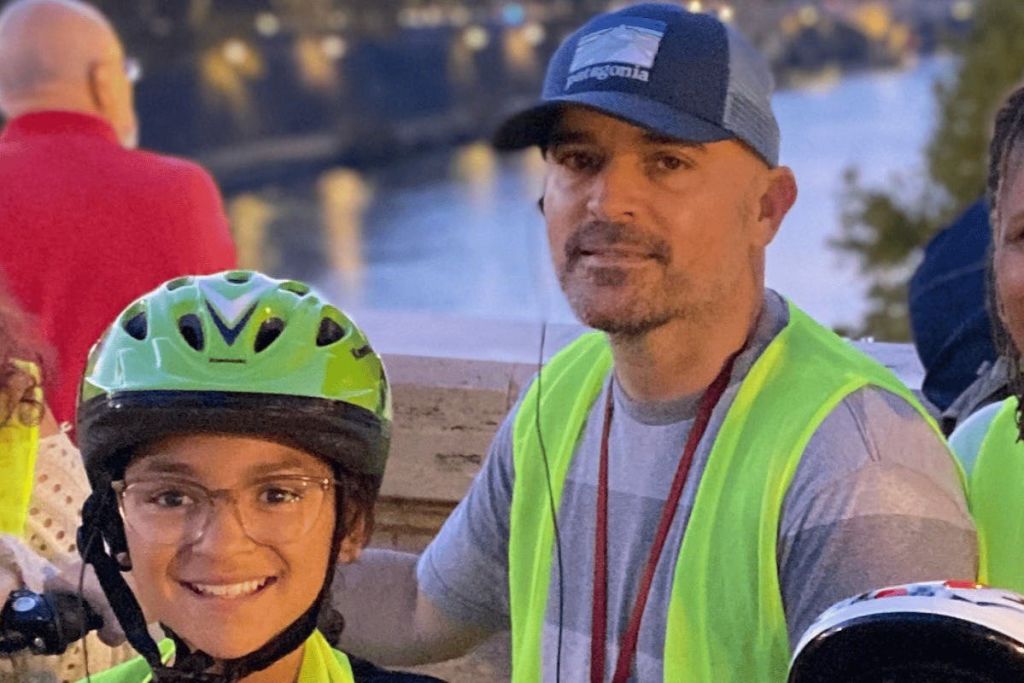 성인과 어린이는 안전 조끼와 헬멧을 착용하고 밤에는 물 근처에서 야외에서 포즈를 취합니다.