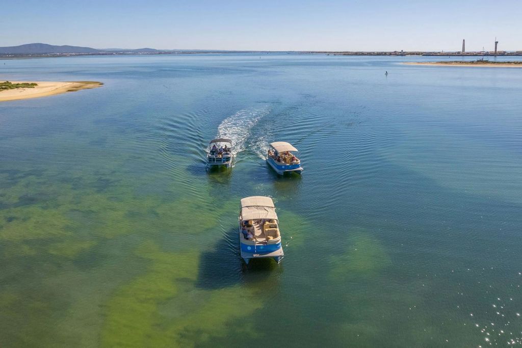 맑고 얕은 푸른 바다를 항해하는 포모사마르 보트와 먼 해안선, 화창한 하늘 아래 등대.