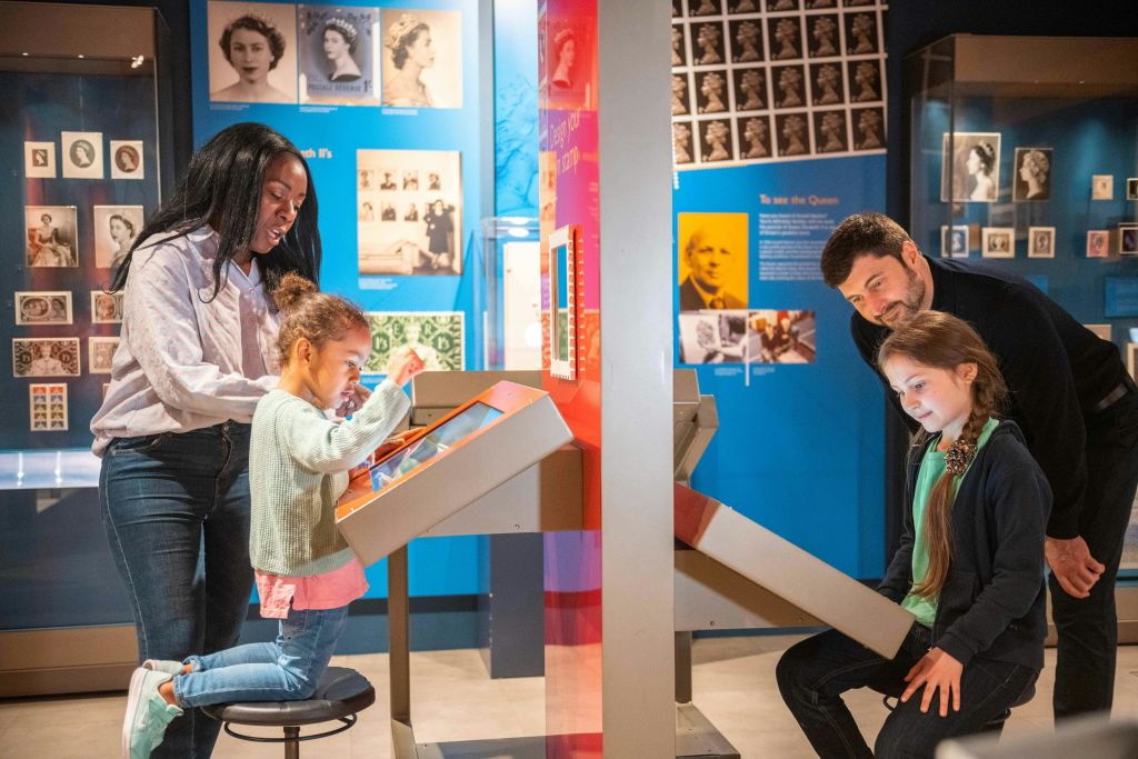 우편 박물관에서 박물관 전시와 상호 작용하는 어린이와 부모.