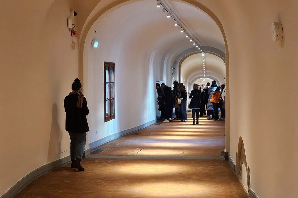 길고 아치형의 복도 맨 끝에 사람들이 모여 있고, 왼쪽 벽에 홀로 서 있는 한 사람이 있었다.