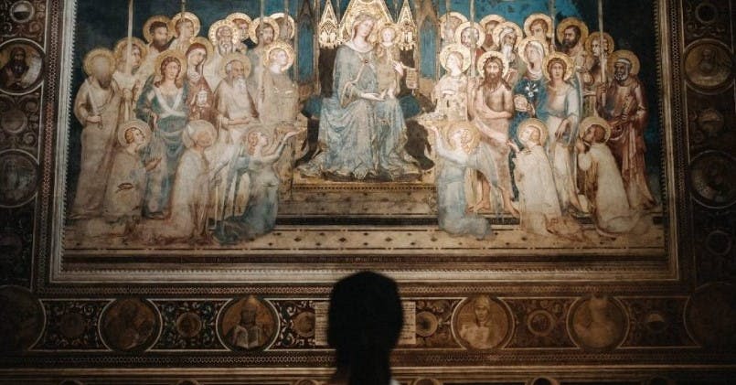 후광이 있는 성스러운 인물들의 무리를 묘사한 종교적 그림. 화려한 디테일과 액자에 담긴 원형 초상화가 장면을 둘러싸고 있습니다.