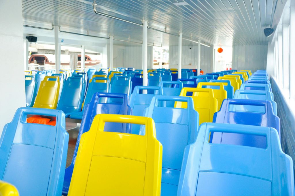 실내 페리 또는 셔틀에 빈 파란색과 노란색 플라스틱 좌석이 줄지어 있습니다.