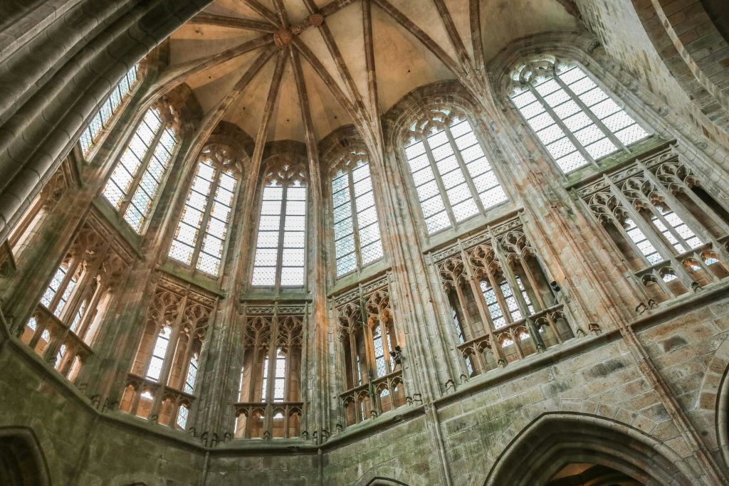 높고 아치형 창문, 정교한 석조 조각, 아치형 천장이 있는 고딕 양식의 대성당 내부.