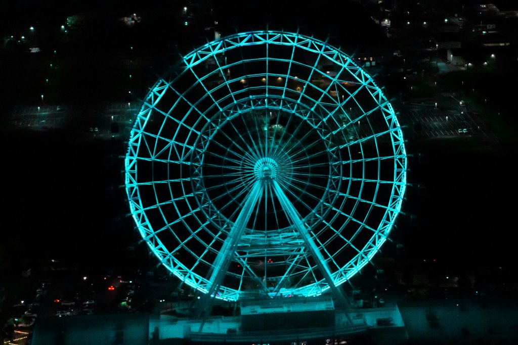어두운 야간 배경에 청록색 조명이 비춰진 크고 빛나는 대관람차.