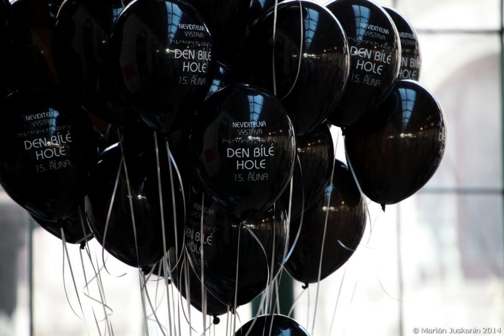 실내 조명과 천장을 반사하는 흰색 문자열에 각각 부착된 검은 풍선 무리.