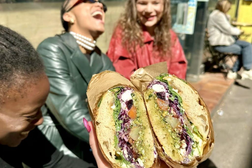 레스토랑 앞을 배경으로 웃고 있는 두 명의 샌드위치와 세 명의 여성