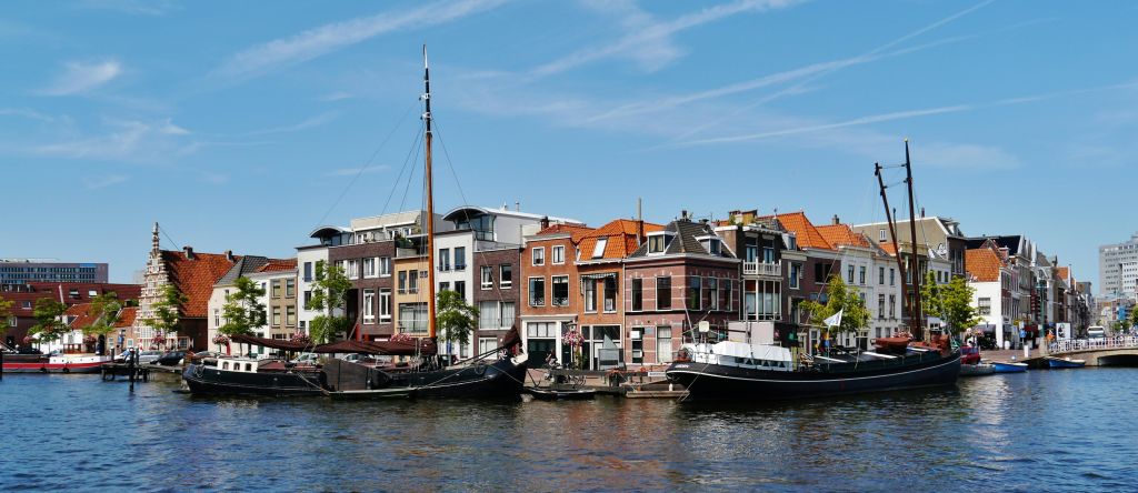 맑고 푸른 하늘 아래 알록달록한 건물 앞에 선착장을 갖춘 요트를 타고 운하를 둘러보세요.