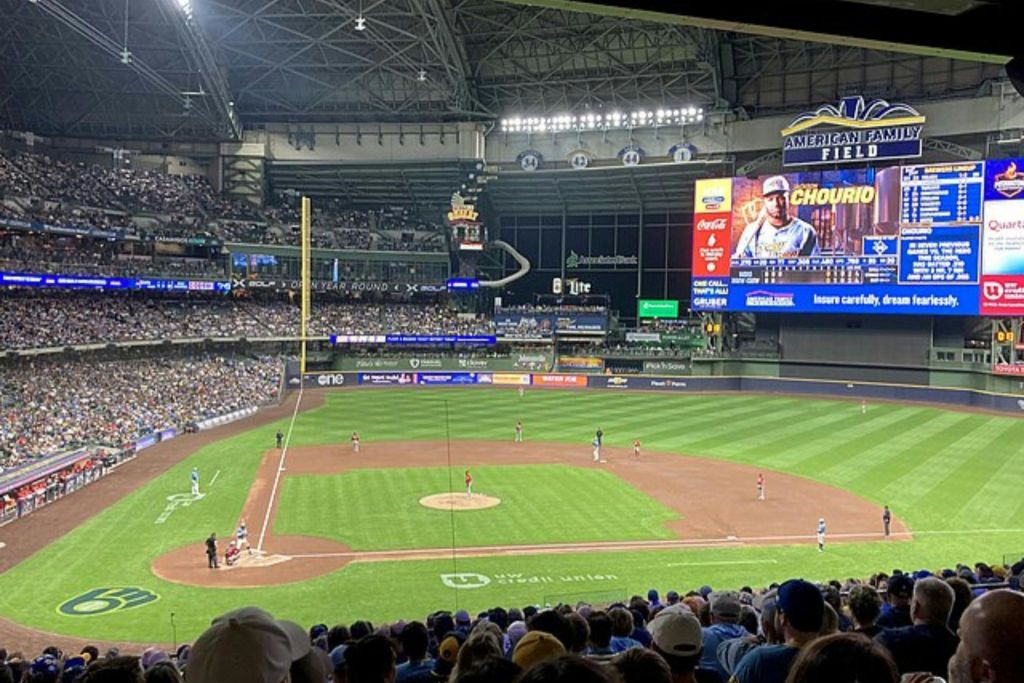 많은 관중과 득점판이 보이는 경기장에서 진행 중인 야구 경기.