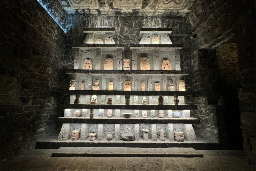 석조 선반은 벽돌 벽에 다양한 고대 조각 유물을 전시하고 있으며, 어두운 환경에서 부드러운 조명으로 조명을 비춥니다.