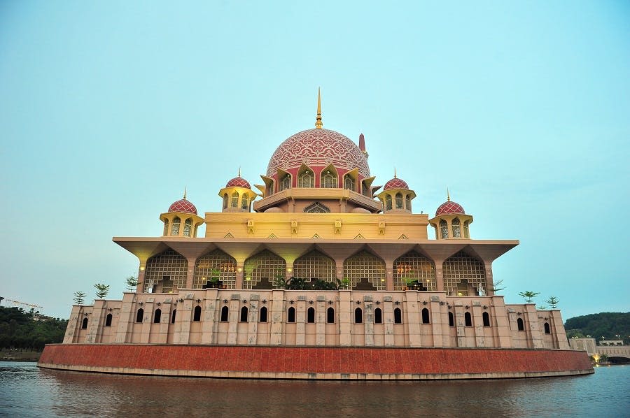 커다란 분홍색 돔과 4개의 작은 돔이 있는 모스크로, 물 건너편에서 바라본 아치형 창문이 특징입니다.
