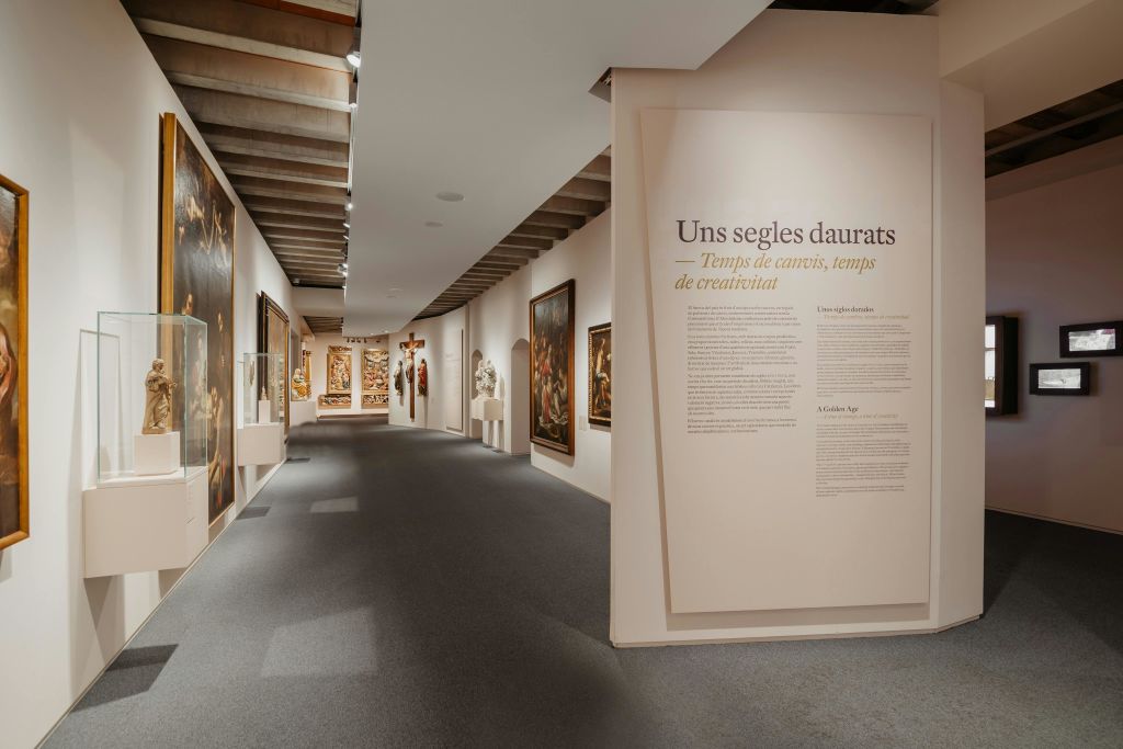 다양한 회화, 조각, "Uns segles daurats" 라는 제목의 벽 텍스트가 있는 아트 갤러리 복도.