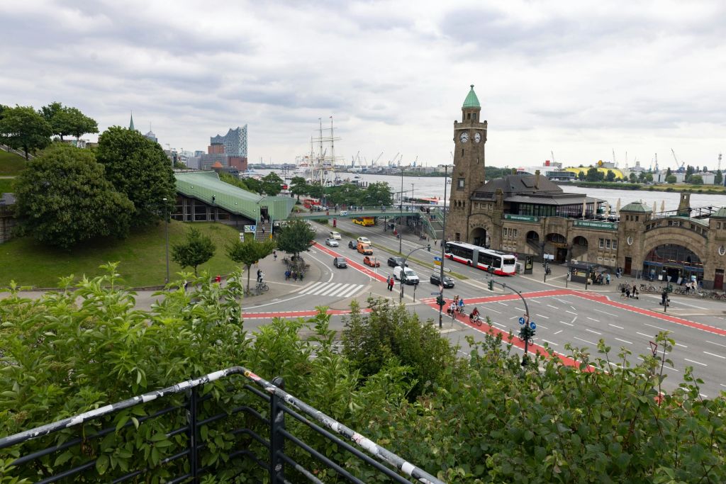 사람, 자동차, 시계탑, 녹음이 우거진 도시 풍경. 흐린 하늘 아래 배와 건물을 배경으로 한 항구.