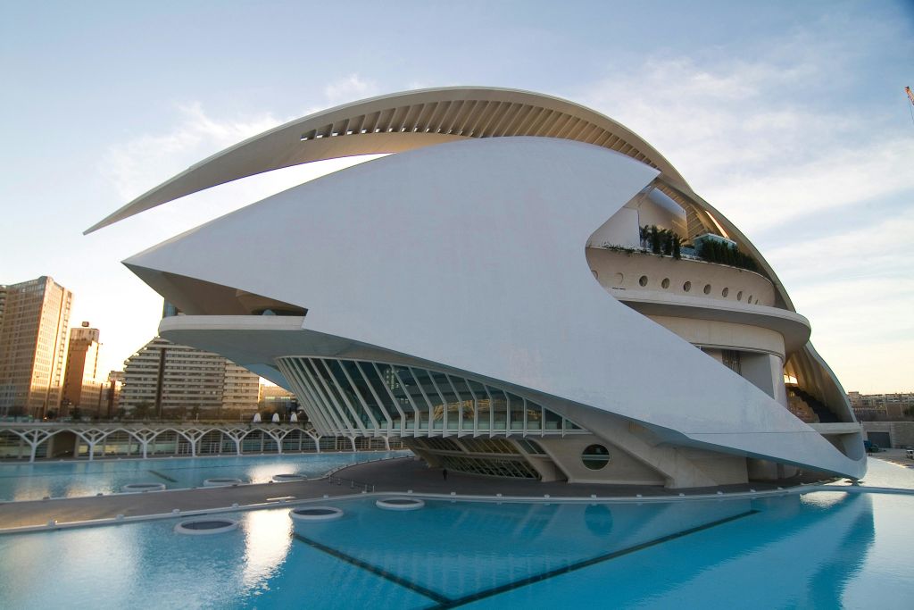 반사 수영장 위에 곡선형 건축물을 갖춘 미래형 흰색 건물로 맑은 하늘을 배경으로 합니다.