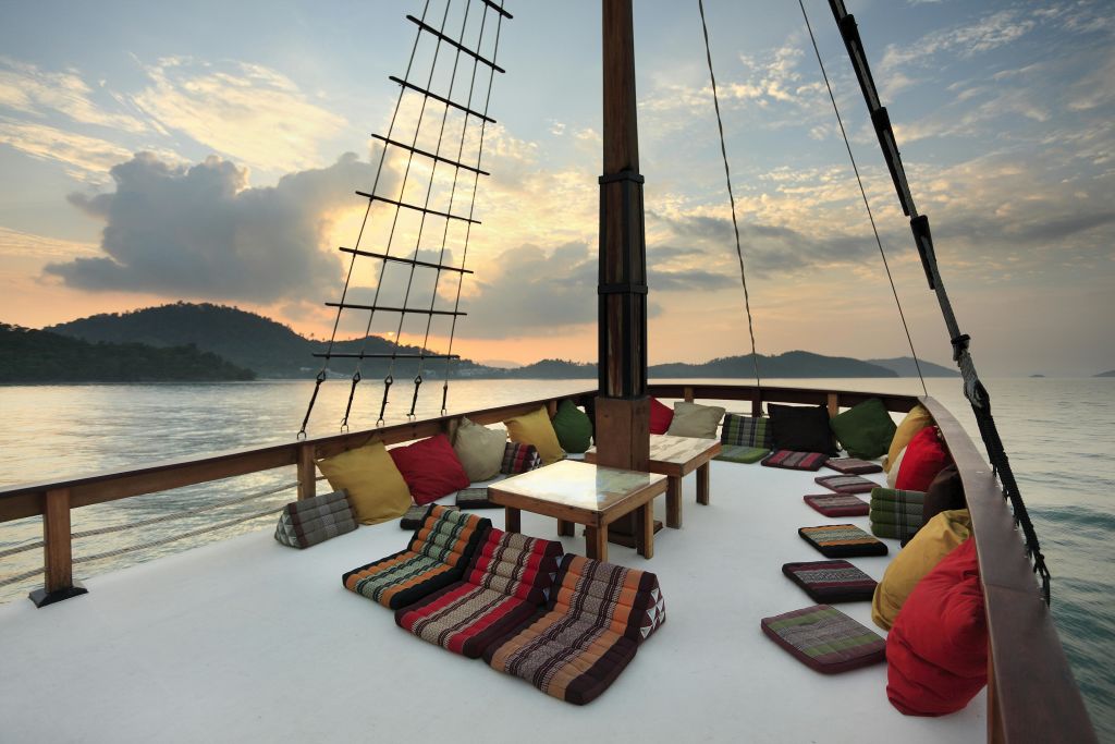 고요한 물과 먼 언덕 위로 석양을 감상할 수 있는 보트 데크에는 다채로운 쿠션과 낮은 테이블이 마련되어 있습니다.