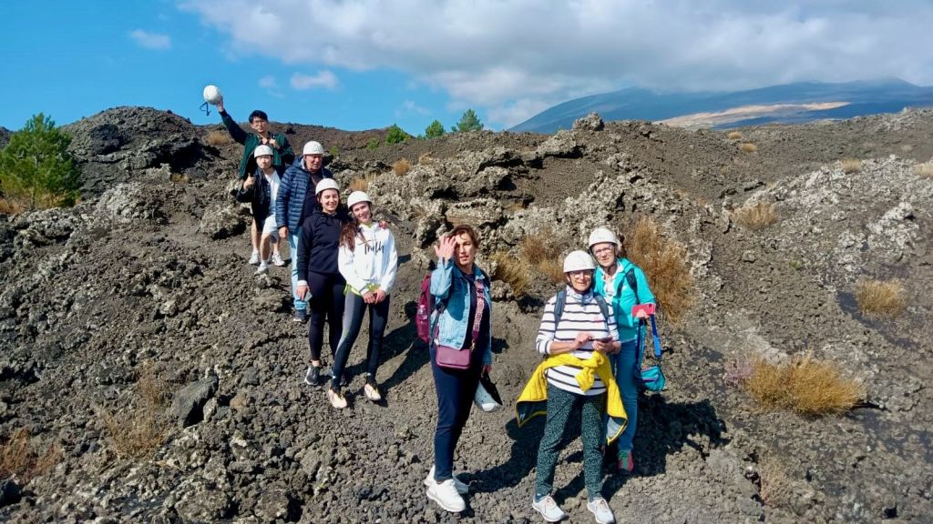 부분적으로 흐린 하늘 아래 바위 지형에 헬멧을 쓰고 야외 의상을 입은 7명의 일행이 서 있습니다.