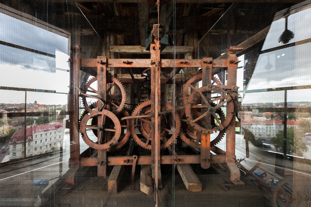 목재 구조에 위치한 크고 녹슨 기어와 유리로 둘러싸인 기계 부품의 복잡한 배치.