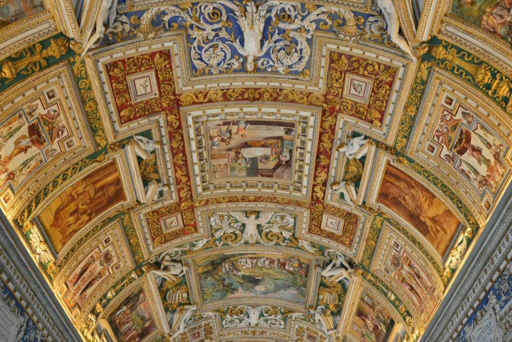 디테일한 프레스코화, 복잡한 패턴, 골드 액센트, 조각된 피규어가 특징인 화려하게 장식된 천장.
