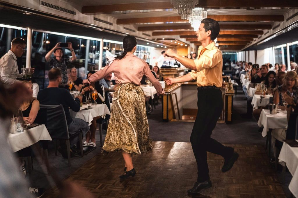 세련된 바닥, 우아한 인테리어, 활기찬 분위기가 돋보이는 레스토랑에서 커플이 춤을 추고 있습니다.