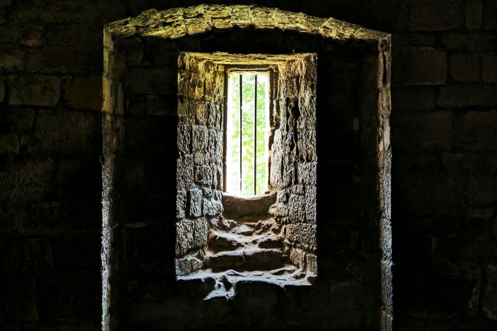 바가 있는 작은 돌 창문은 풍화된 돌담으로 둘러싸여 빛을 비출 수 있습니다.