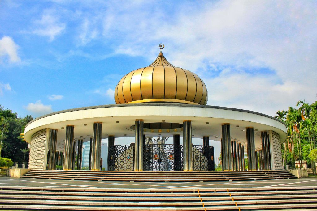 커다란 황금 돔과 검은 기둥이 있는 기념비로, 부분적으로 흐린 하늘 아래로 이어지는 원형 계단이 특징입니다.