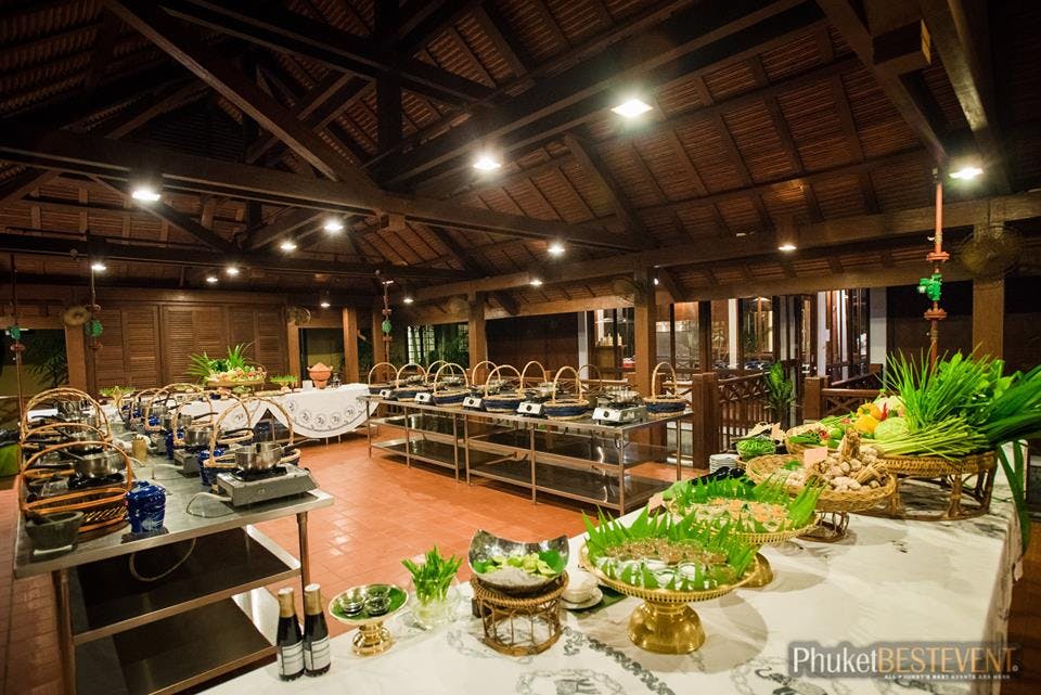 나무 지붕 구조 아래 다양한 요리가 전시된 실내 뷔페 시설로 화려한 서빙 플래터와 녹색 장식이 특징입니다.