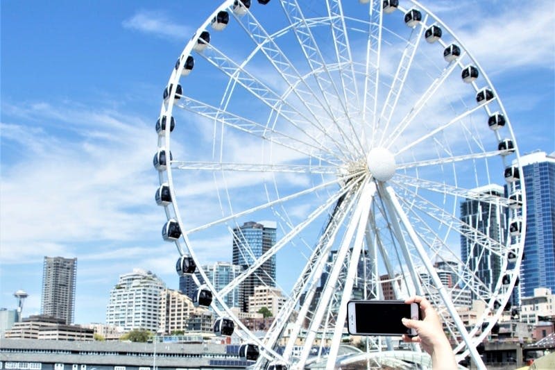 물가에서 바라본 시애틀 그레이트 휠 (Seattle Great Wheel) 에서 게스트는 전면에서 아이폰 사진을 찍고 있습니다.