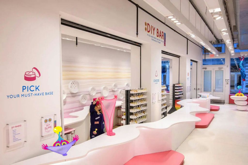 밝은 조명으로 꾸며진 현대적인 공간 안에 있는 DIY 바 카운터에서 어린이가 분홍색 점액을 펴고 있습니다.