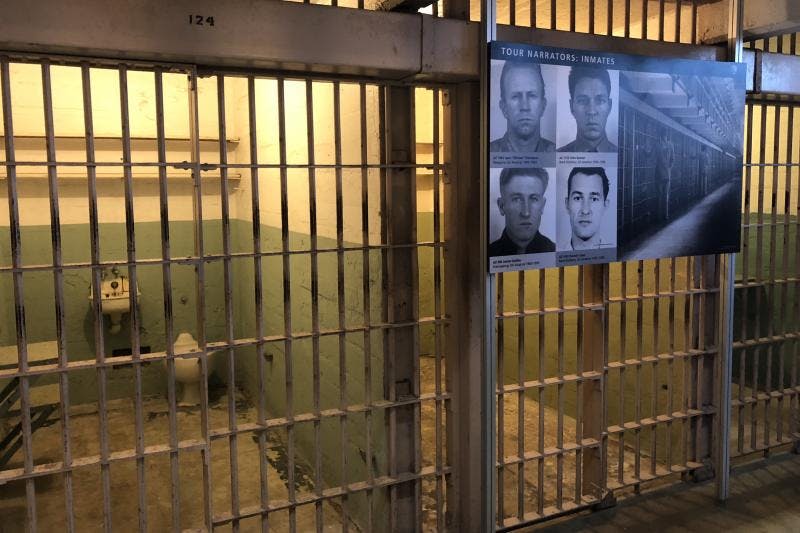 수감자 사진과 교도소 현장의 포스터, 낡은 금속 문이 있는 수감실 옆에 전시되어 있습니다.