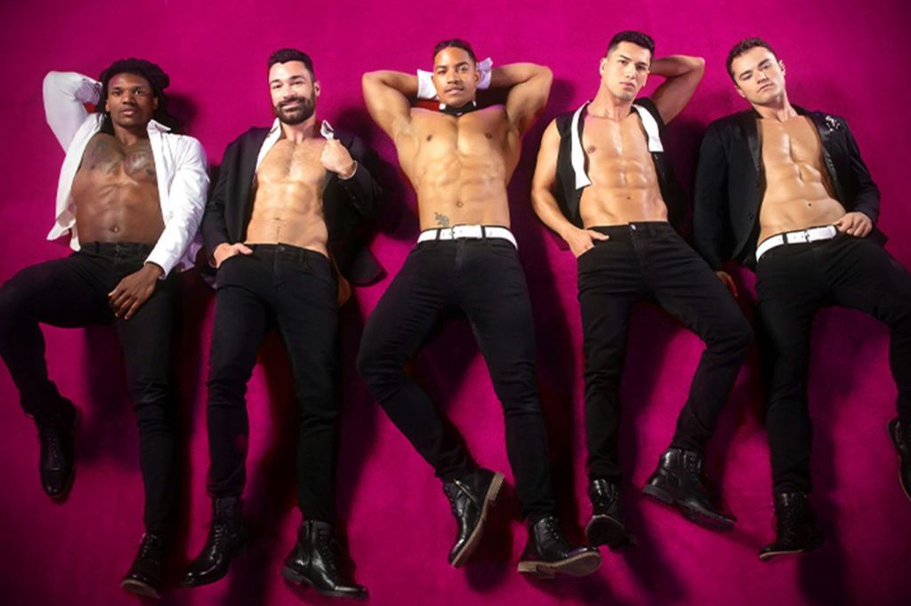 부분적으로 오픈된 블레이저와 청바지를 입은 셔츠 없는 남성 5명이 밝은 분홍색 배경에서 포즈를 취하고 있습니다.