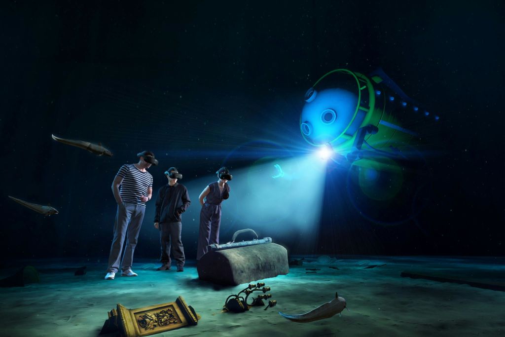 VR 헤드셋을 착용한 두 사람이 수중 유적 근처에 서 있으며, 근처에 스포트라이트가 있는 로봇 잠수정이 있습니다.