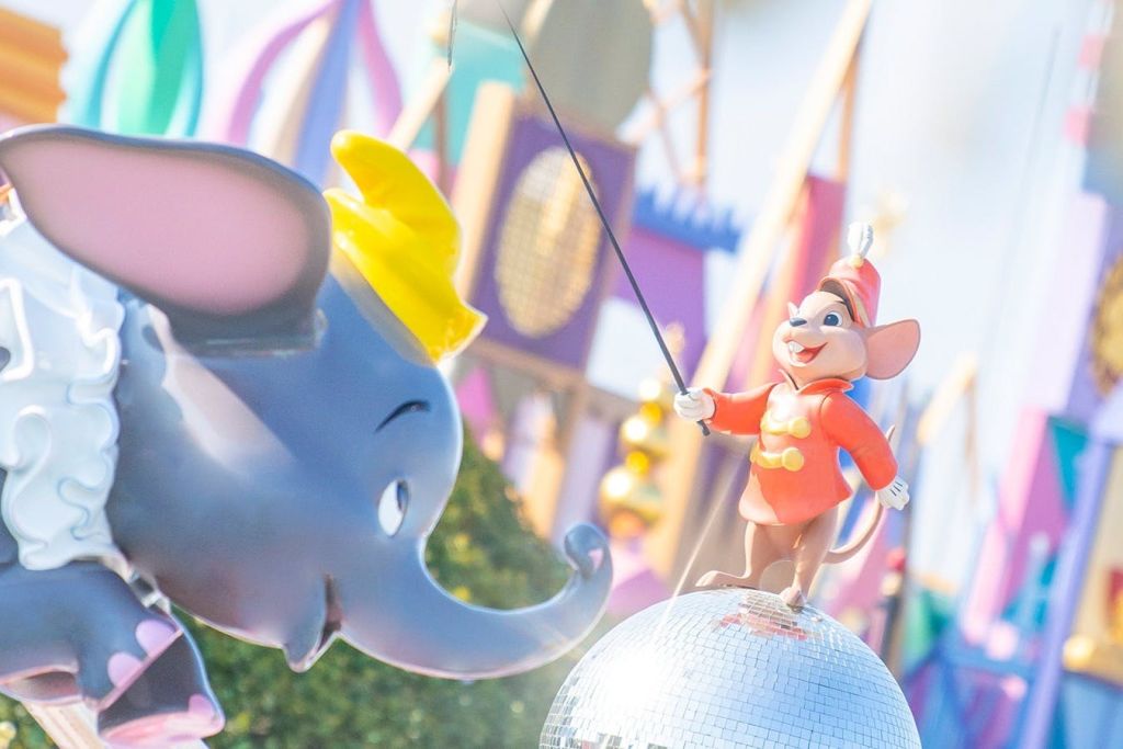 빨간색 재킷과 모자를 쓴 덤보와 쥐의 조각입니다. 마우스는 디스코 볼 위에 서 있고 덤보는 왼쪽에 있습니다.