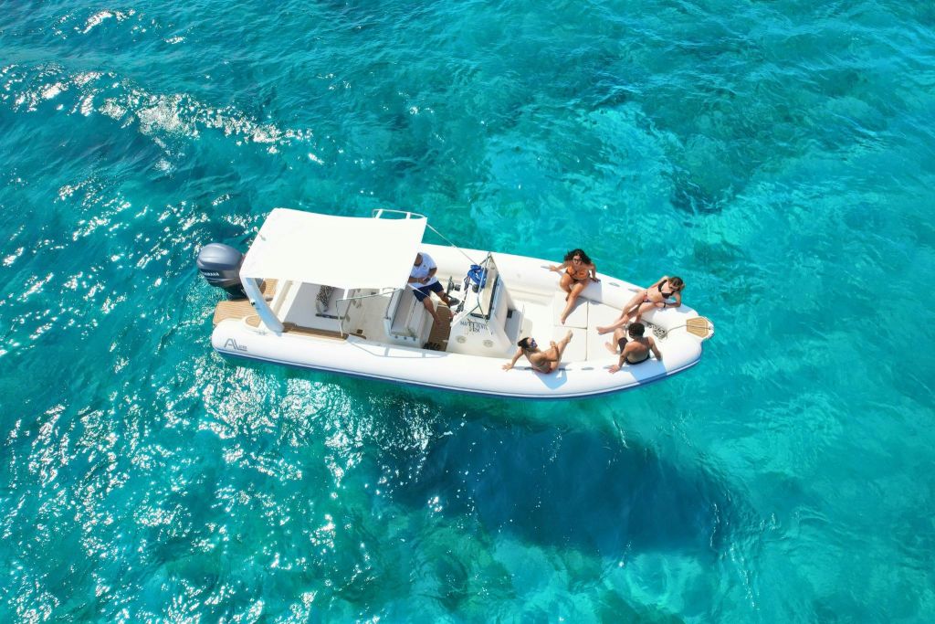 맑고 푸른 물 위에 캐노피가 있는 작은 흰색 보트에 사람들이 태양 아래에서 휴식을 취하고 있습니다.