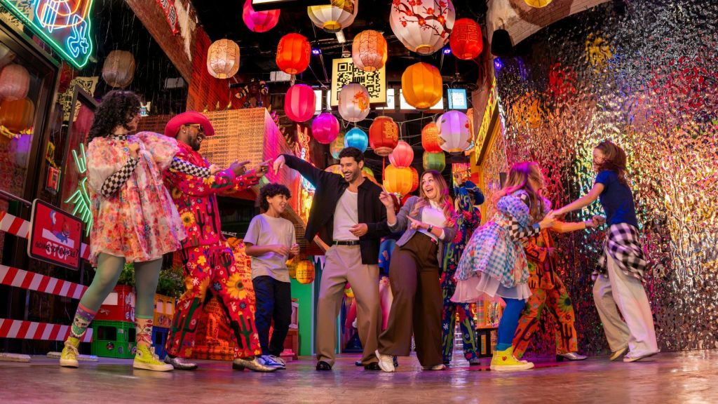 축제 분위기의 실내에서 화려한 등불 아래에서 즐겁게 춤을 추는 사람들.