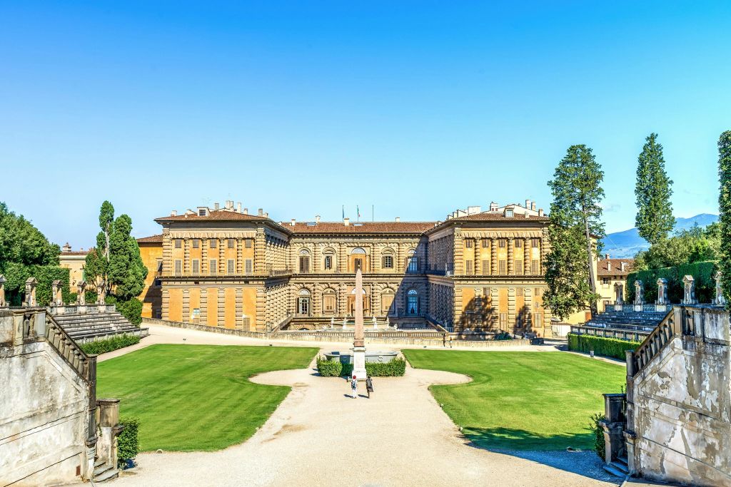 푸른 하늘 아래 푸른 잔디밭으로 둘러싸인 튼튼한 건축물이 있는 역사적인 대형 건물입니다.