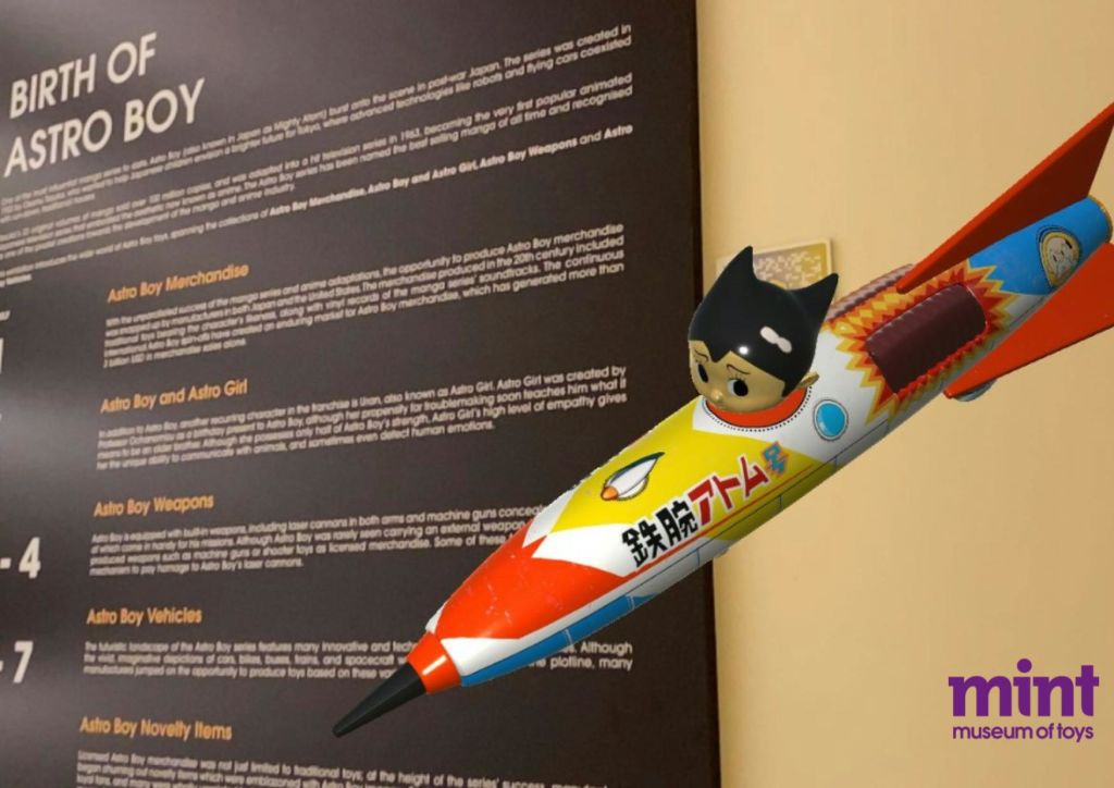 로켓 수트를 입은 아이의 작은 조각상이 노란색 벽에 부착되어 있으며, 텍스트 디스플레이 보드 옆에 있습니다.