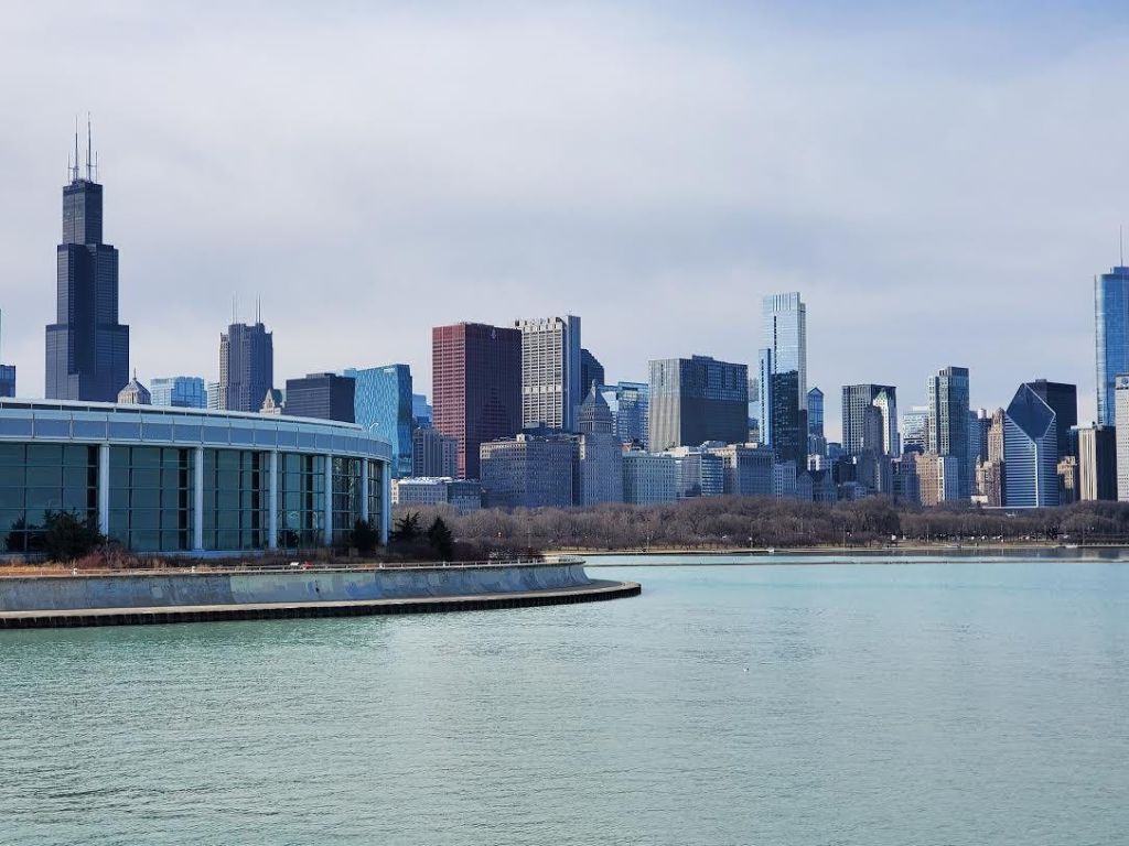 좌측에 현대적인 건물이 있는 물가에 보이는 높은 건물이 있는 도시의 스카이라인.