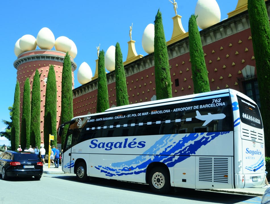 달걀 모양의 조형물과 편백나무가 있는 독특한 건물 옆에 투어 버스가 주차되어 있습니다. 사람들이 버스 근처에 있습니다.