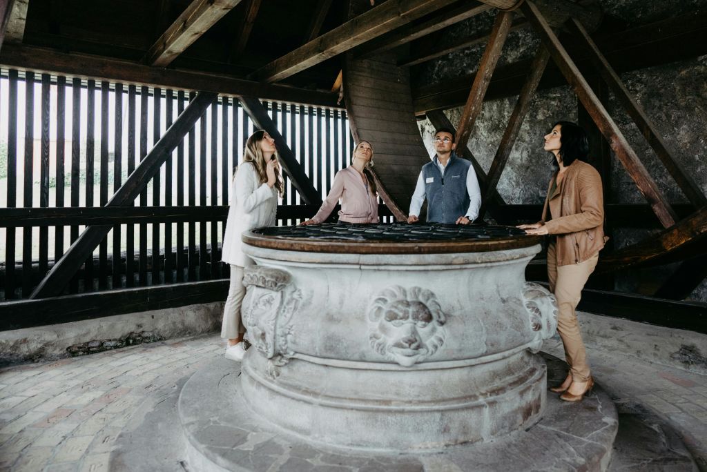 나무 구조물 안의 크고 화려한 돌 주위에 네 명이 서서 세심하게 올려다보고 있습니다.