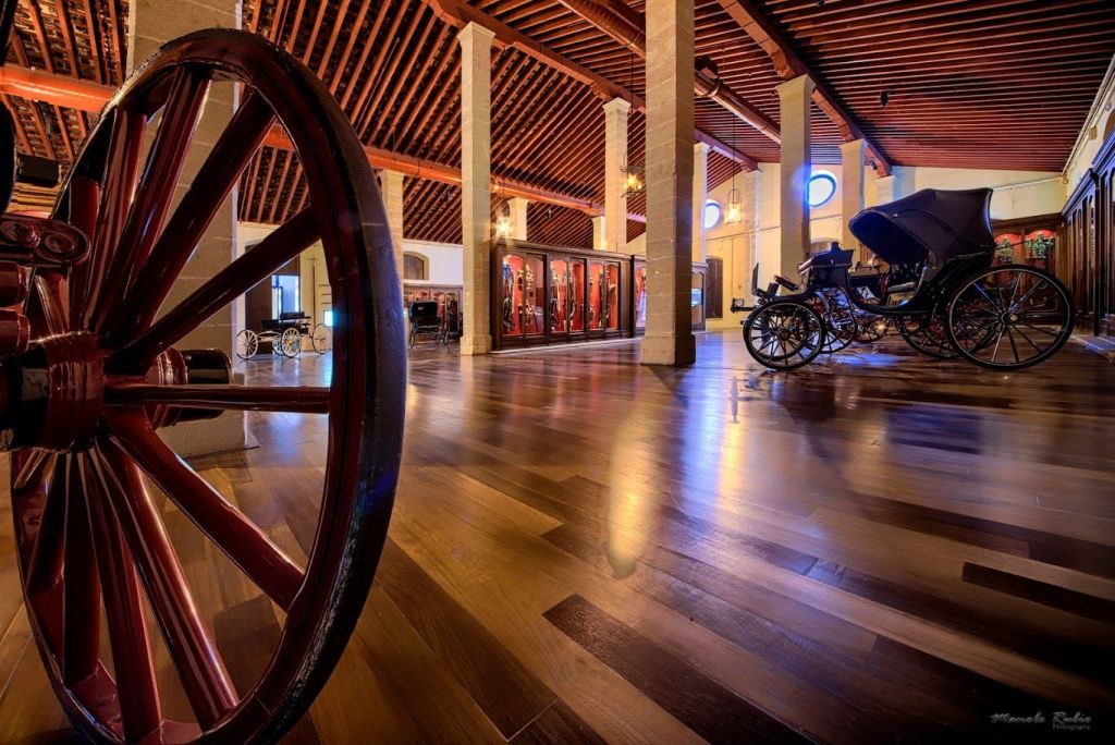 나무 바닥, 전시 케이스, 빈티지 마차, 빨간색 마차 바퀴가 있는 넓은 박물관 홀.