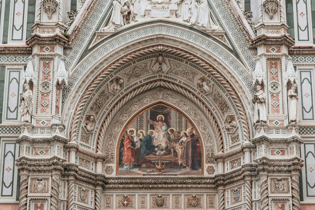 종교적 인물을 묘사한 정교한 프레스코화와 고딕 양식의 아치 아래 정교한 조각이 돋보이는 화려한 건축 디테일.
