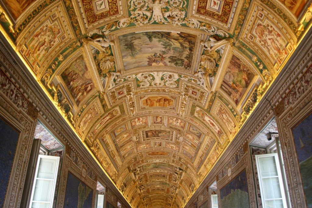 정교한 그림과 디테일한 조각이 돋보이는, 화려하게 장식된 금색 아치형 천장이 있는 홀.