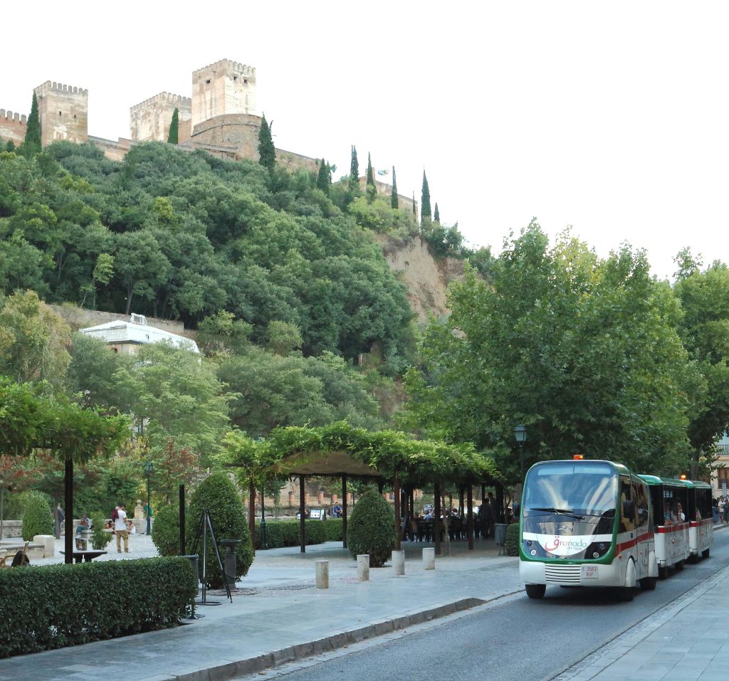 나무가 우거진 도로를 달리는 화이트 투어 버스는 언덕에 있는 유서 깊은 성을 배경으로 운행됩니다.