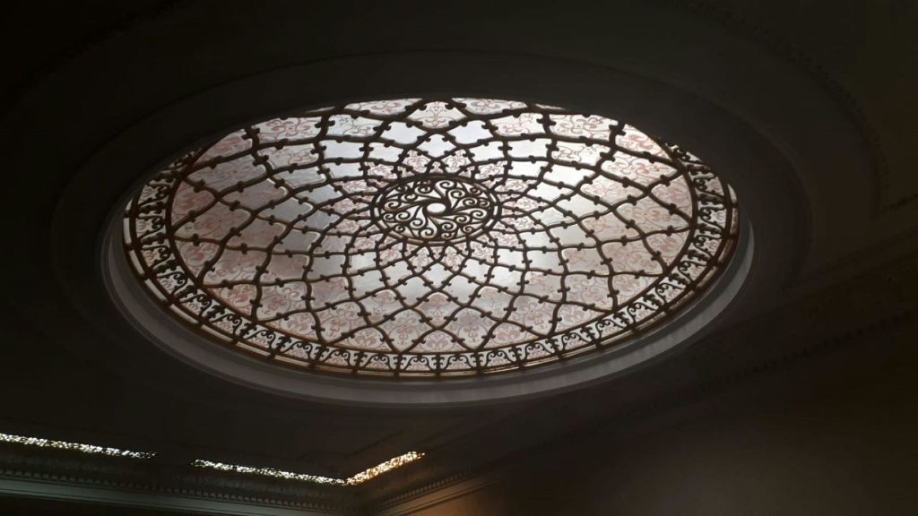 대칭적인 기하학적 패턴과 섬세한 꽃 디자인이 돋보이는 정교한 타원형 스테인드글라스 천장입니다.