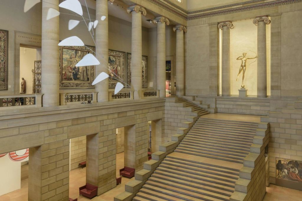 기둥, 태피스트리, 이동식 조각품, 동상을 배경으로 한 박물관의 웅장한 계단.