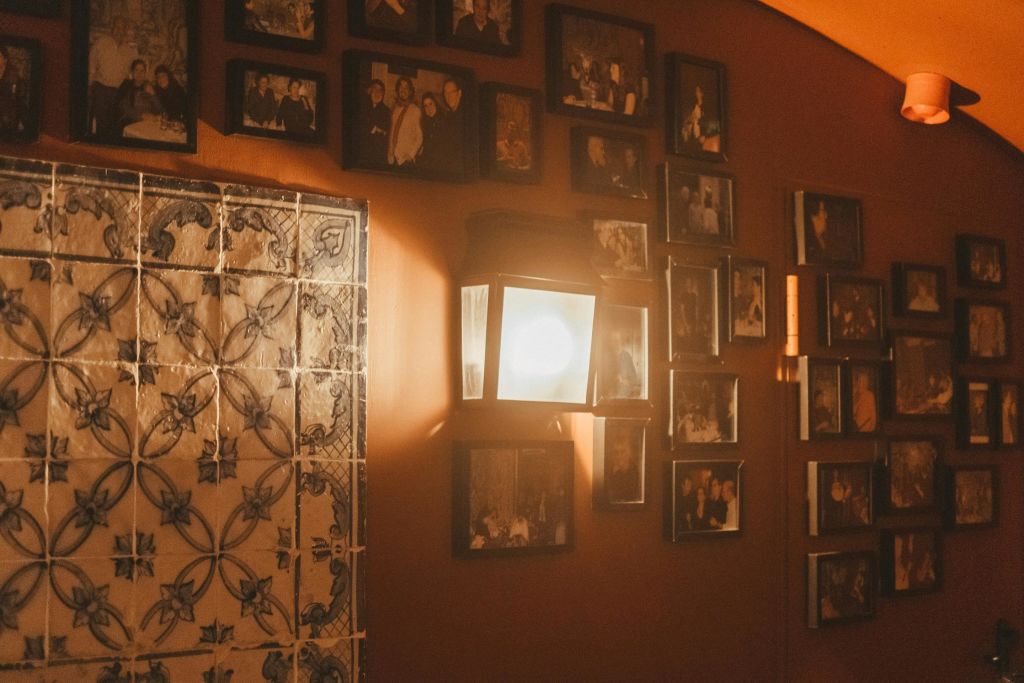 벽에 설치된 램프는 액자에 담긴 사진과 장식용 타일을 주황색 벽에 비춥니다.