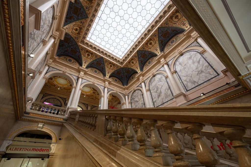 화려한 아치, 대리석 벽, 장식 천장, 디테일한 난간이 있는 계단이 있는 웅장한 인테리어입니다.