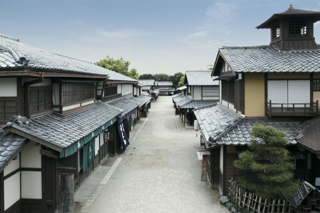 목조 건물, 타일로 마감된 지붕, 푸른 하늘이 있는 조용하고 텅 빈 일본 전통 거리입니다.